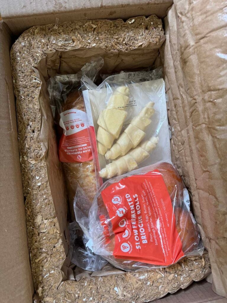 A wildgrain box filled with croissants, rolls and bread