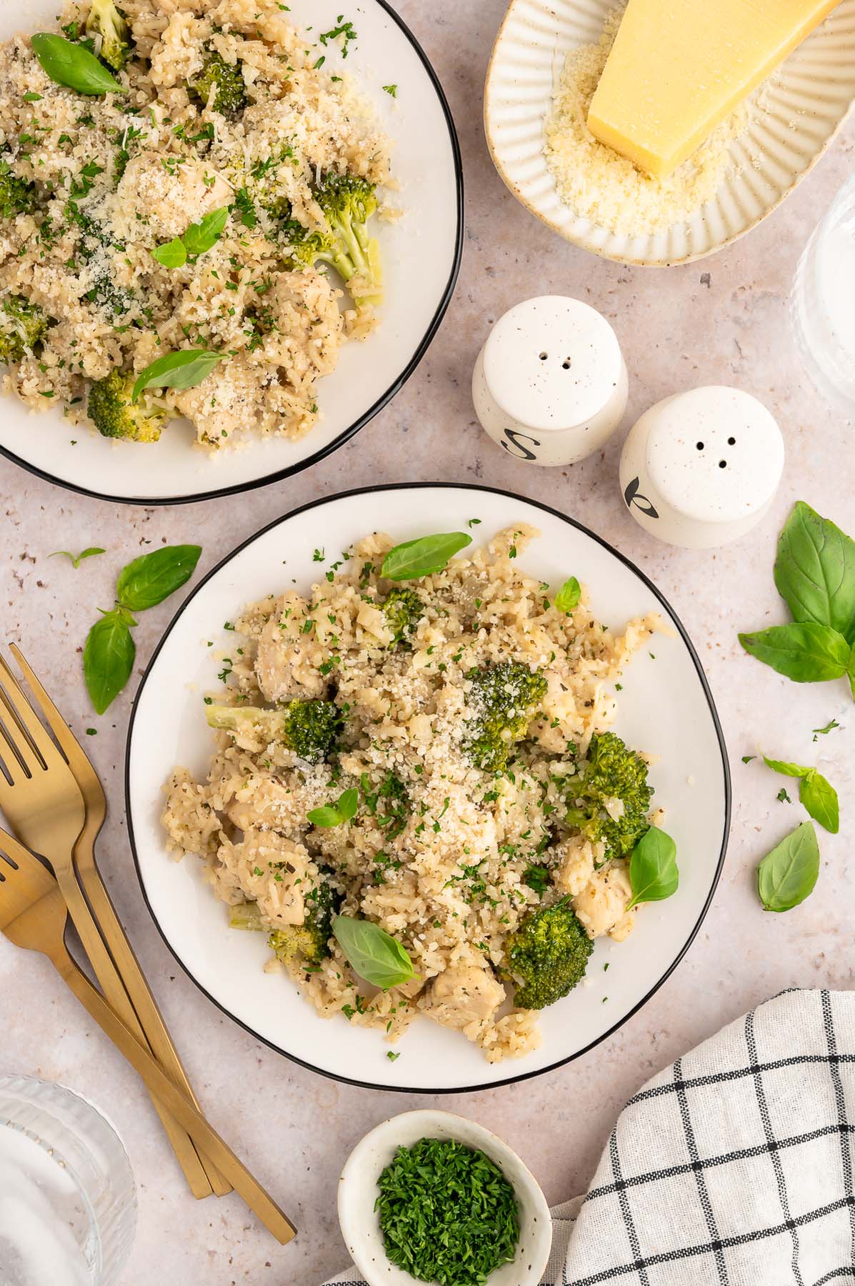 Healthy chicken and broccoli dinner on two plates, with two forks and salt and pepper shakers on the side. 