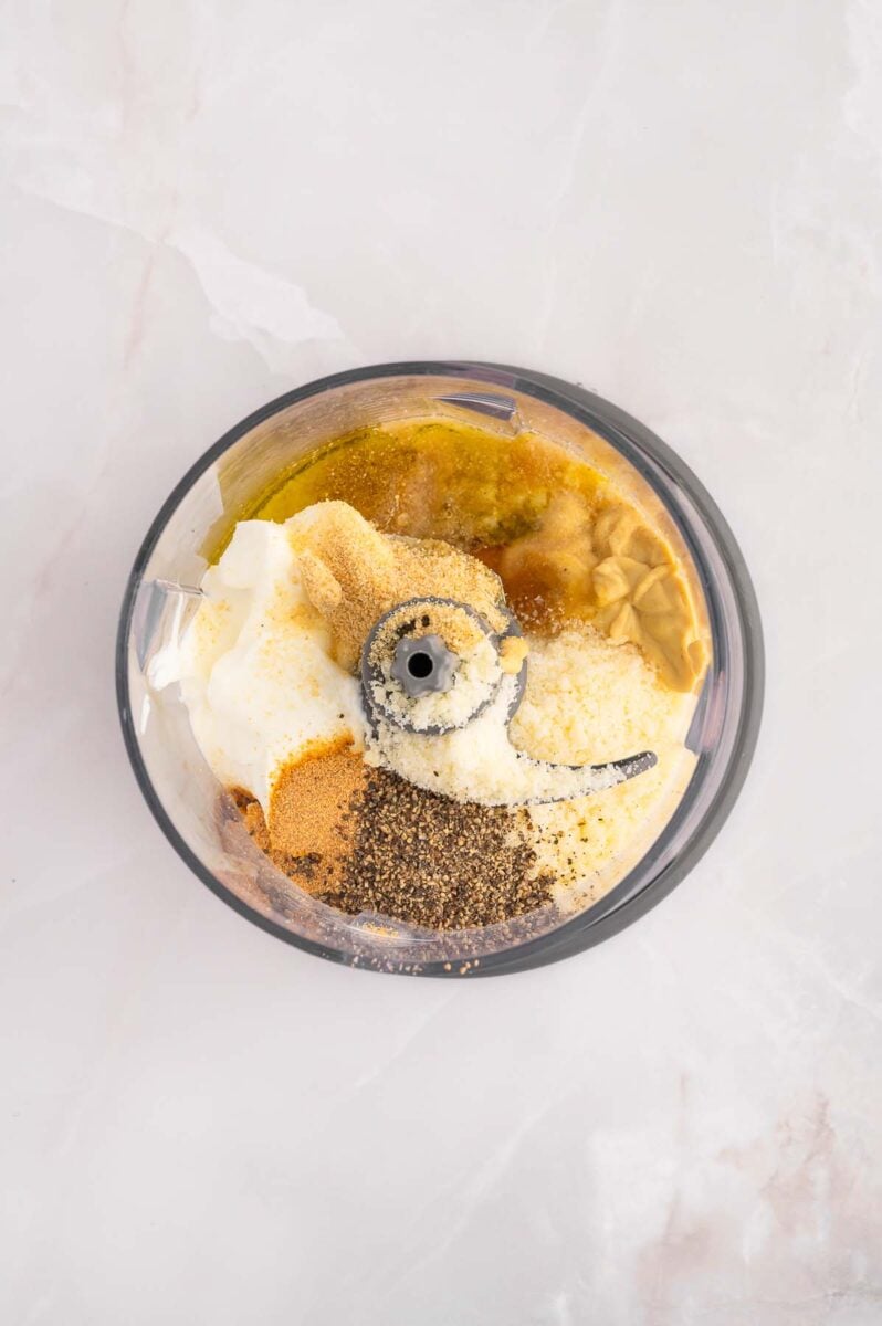 Ingredients for caesar salad dressing in a small food processor before blending.