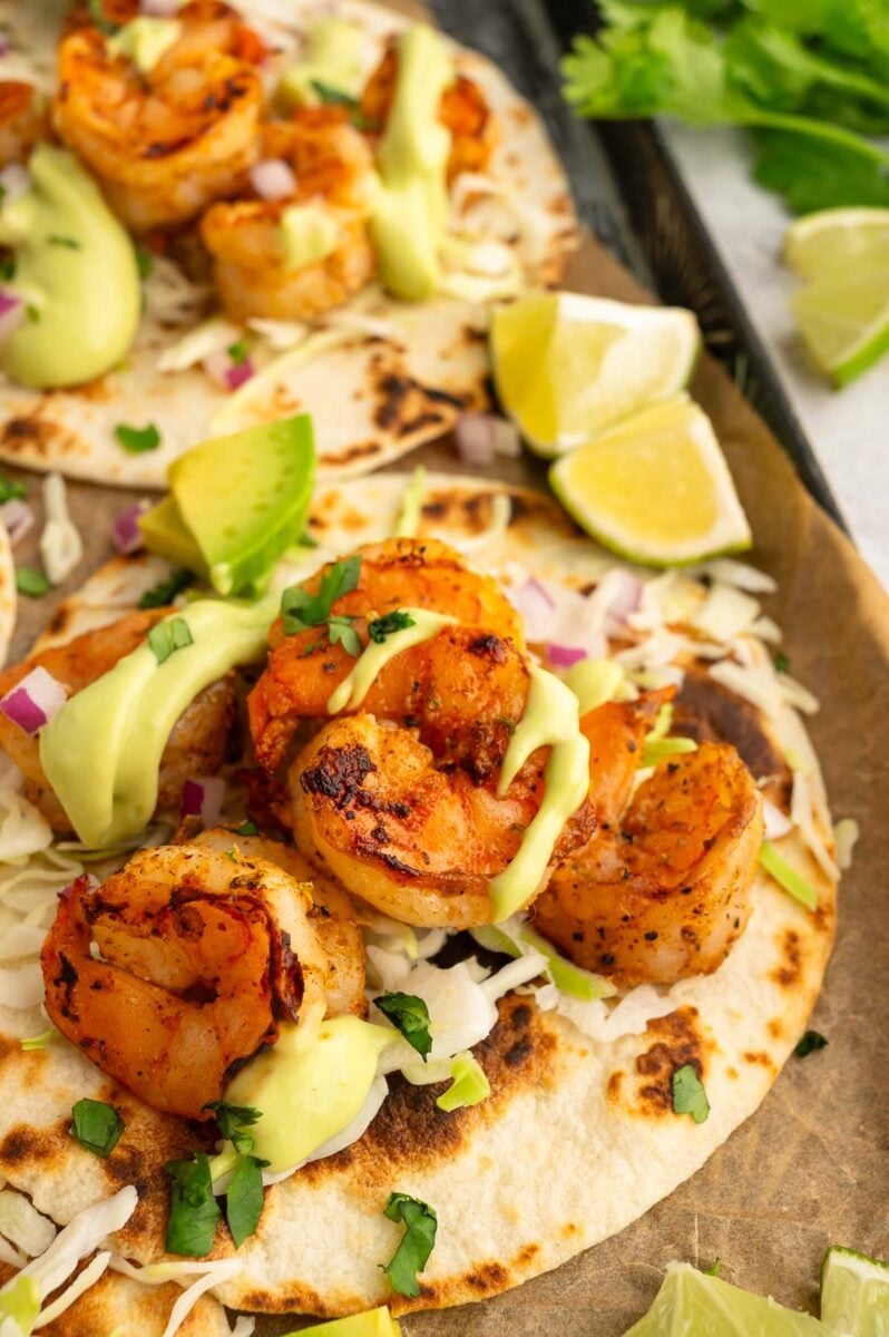A close up of chili lime shrimp on a taco shell with another shrimp taco in the background.