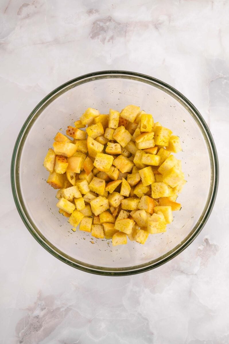 Cubed bread tossed in olive oil in a bowl.