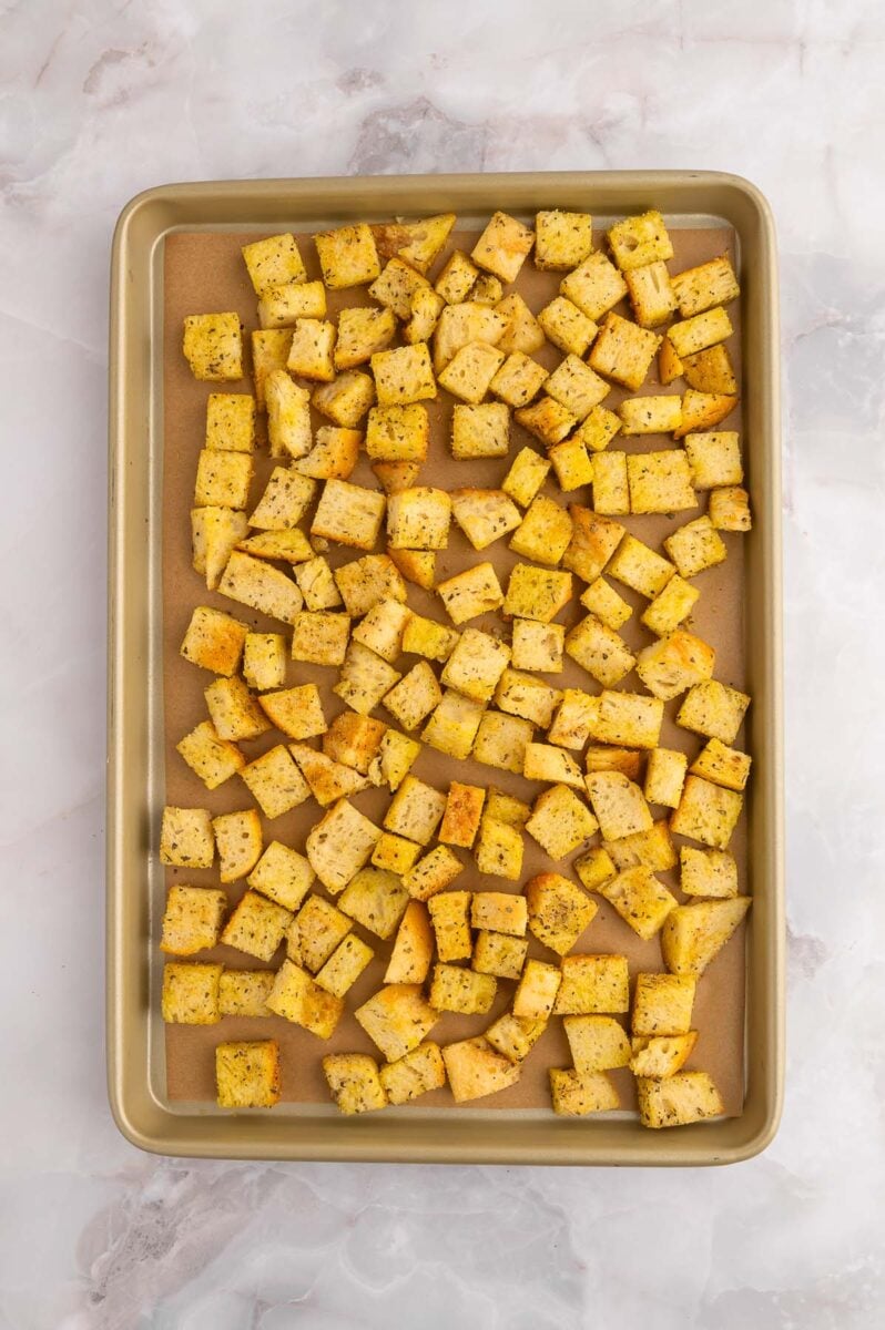 Uncooked croutons on a parchment lined baking sheet.