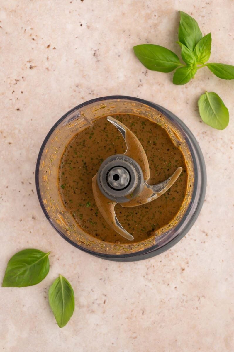 Homemade Balsamic dressing in a small food processor with fresh basil on the side.