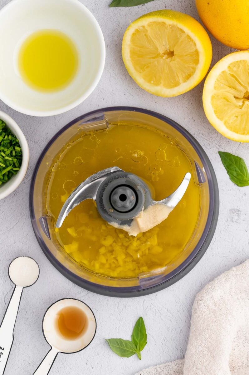 Tahini, olive oil, lemon juice, cold water, maple syrup, minced garlic, and salt in a food processor before blending.