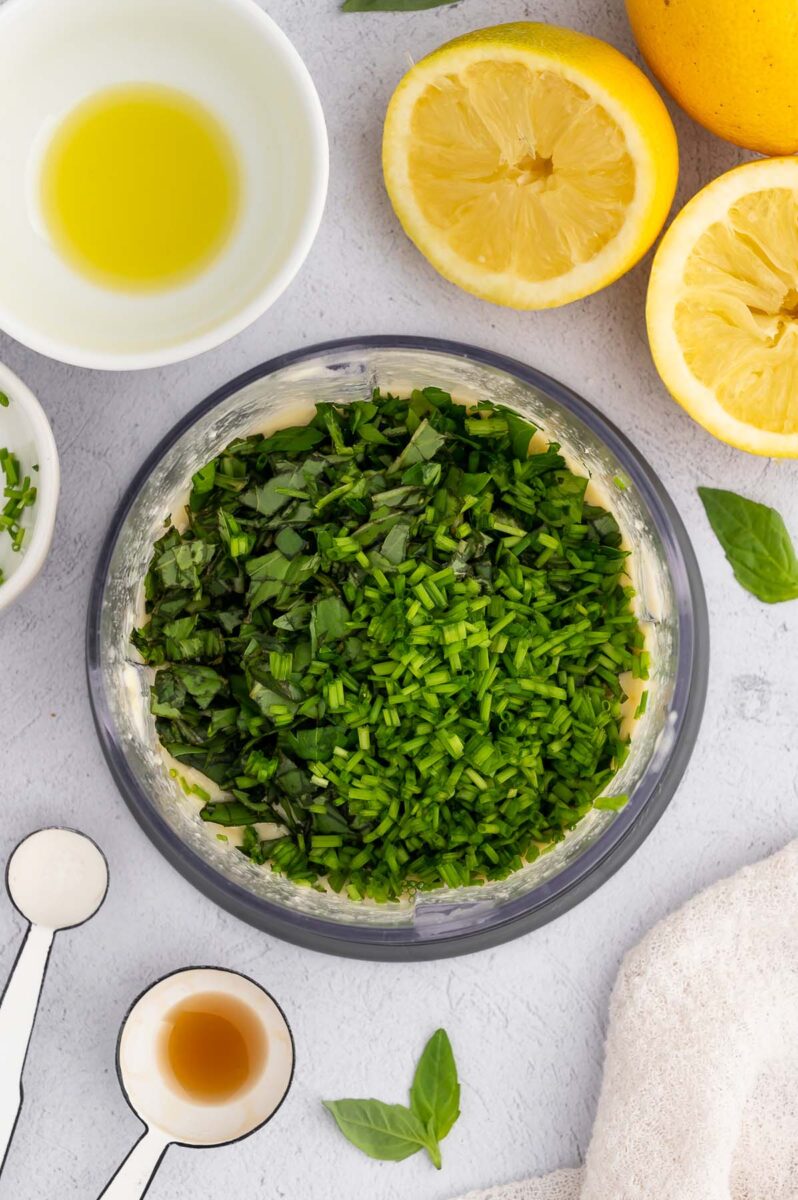 Tahini dressing topped with fresh herbs before mixing in.