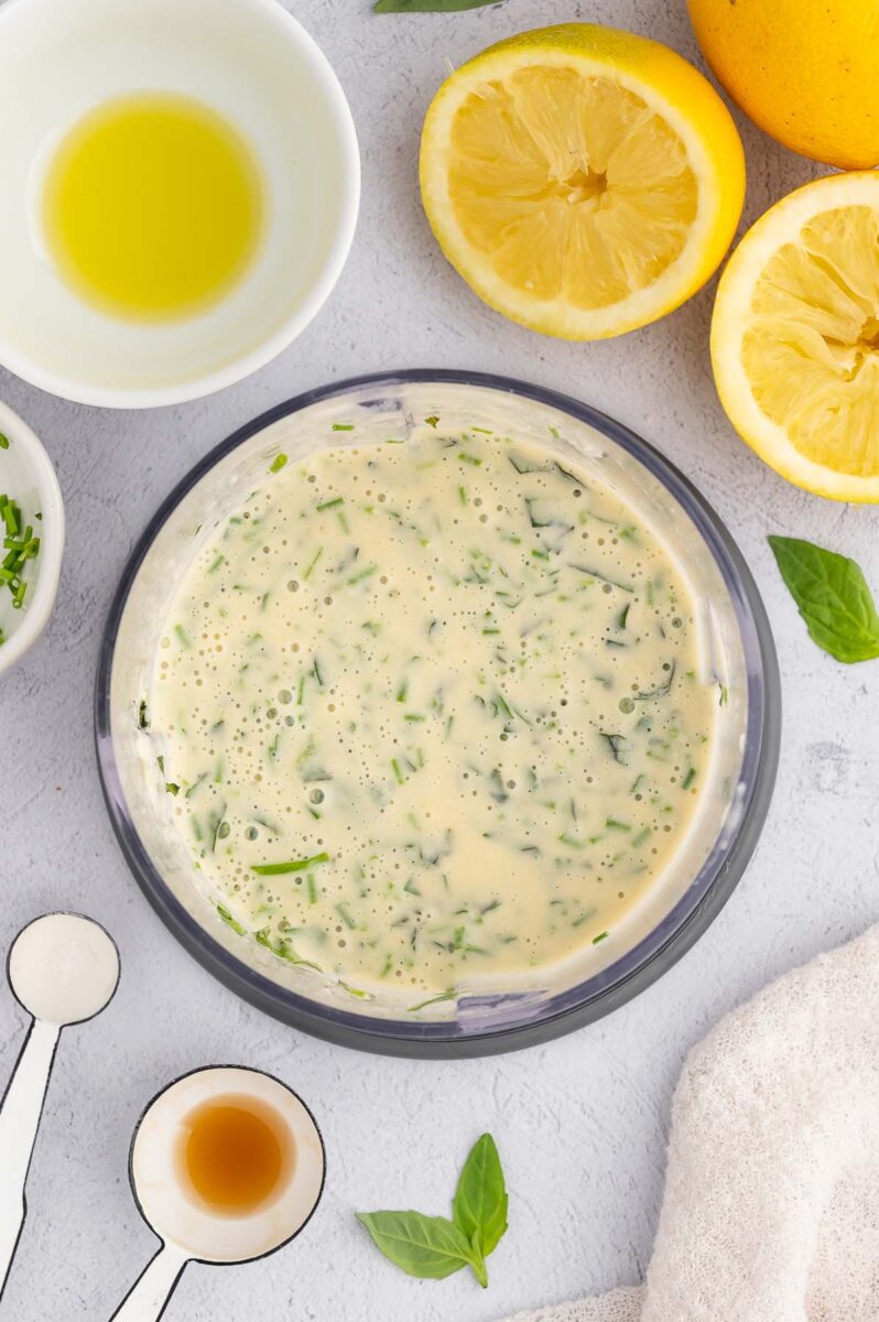 Tahini dressing in a bowl with lemons on the side.