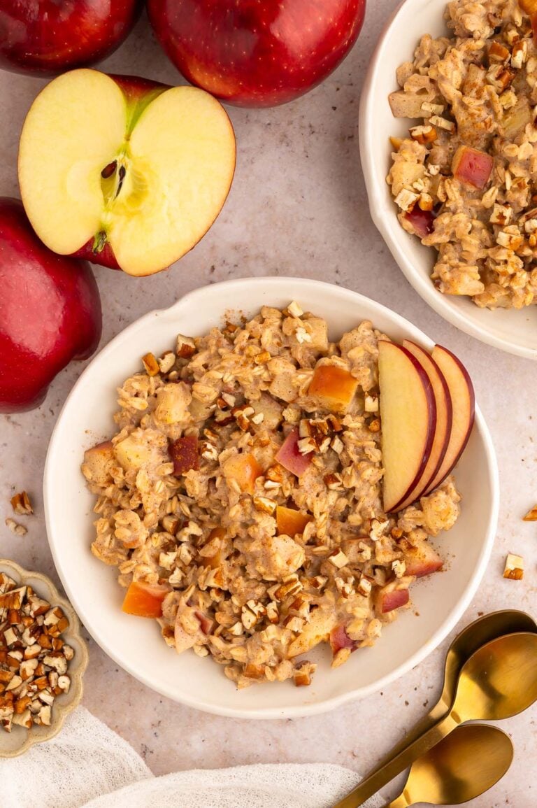 Apple Oatmeal in a shallow white bowl with sliced apples garnishing and another bowl on the side.