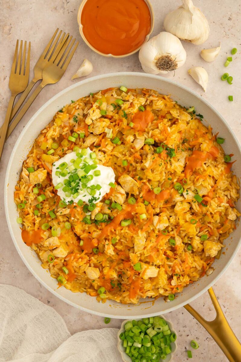 Buffalo Chicken and Rice in a skillet with a bowl of buffalo sauce on the side.