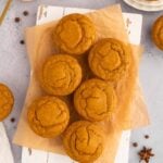 Pumpkin protein muffins on a piece of parchment paper with pumpkin puree in a bowl on the side.