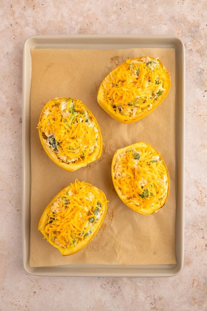 Four buffalo chicken spaghetti squash boats on a parchment lined baking sheet.