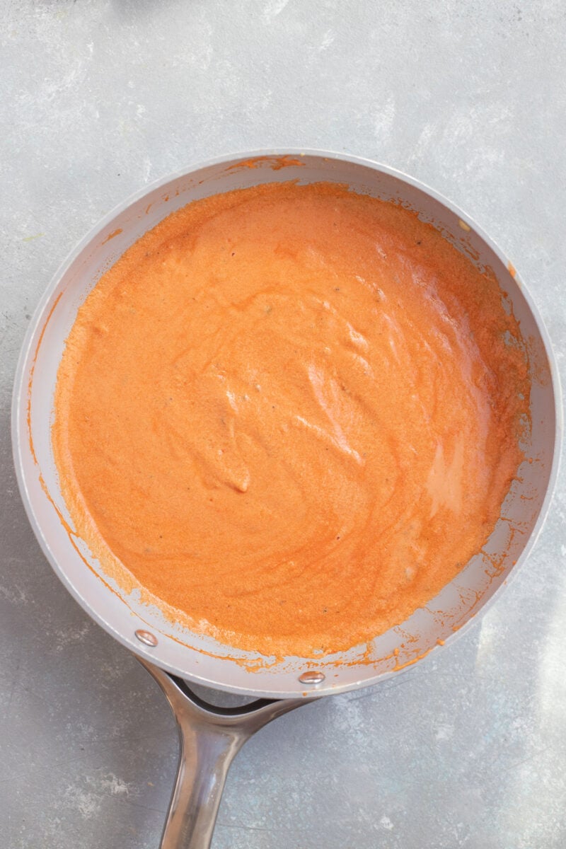 Penne Vodka Sauce in a sauce pan on a grey background.