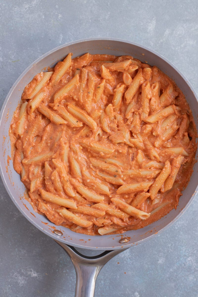 Healthy Penne alla Vodka in a saucepan on a grey background.