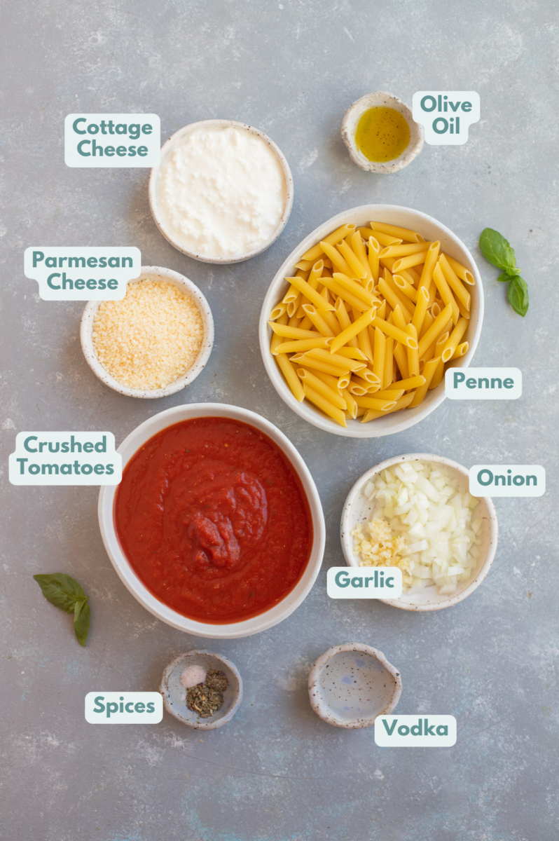 Ingredients for healthy penne vodka in bowls on a grey background.
