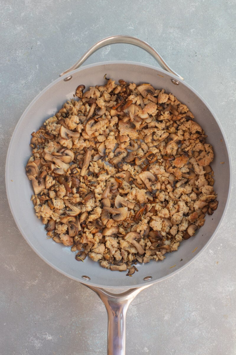 Browned ground sausage and mushrooms in a pan for a sausage stuffing.