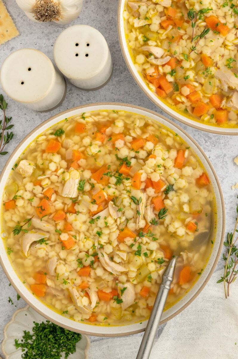 Chicken Stars Soup in a bowl with a spoon resting in the bowl with another bowl on the side.