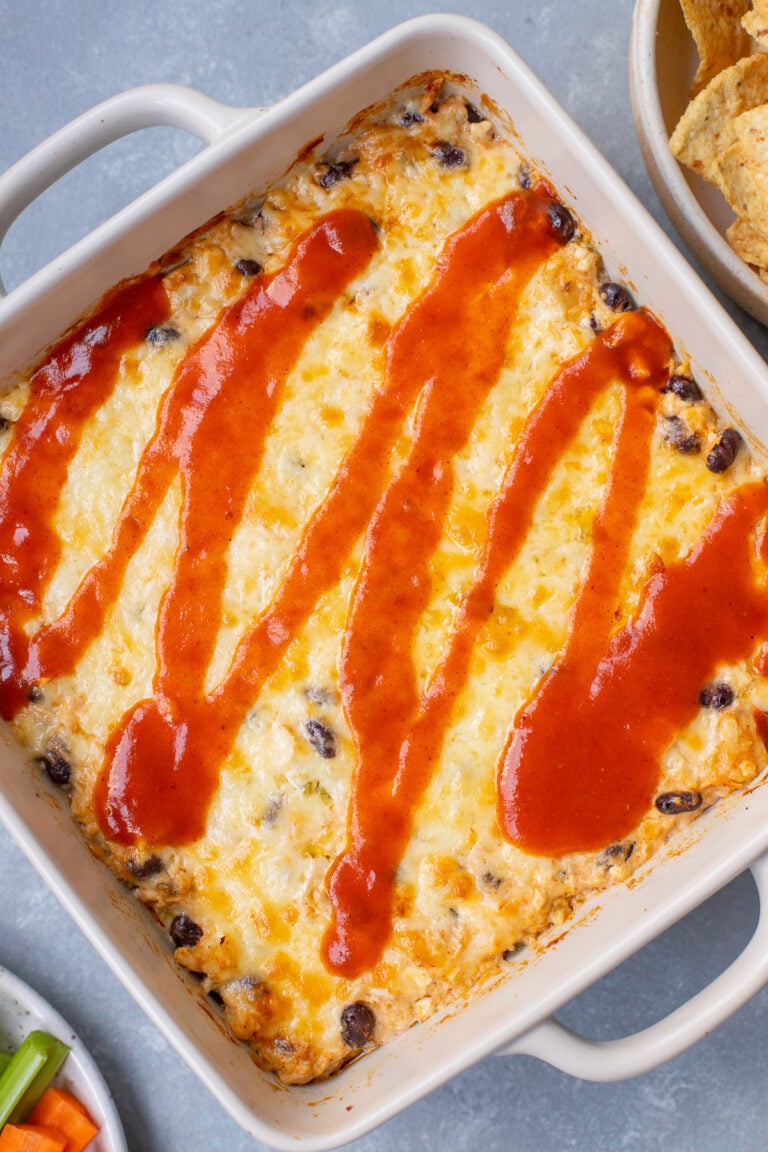 Chicken Enchilada Dip in a baking dish topped with more enchilada sauce.