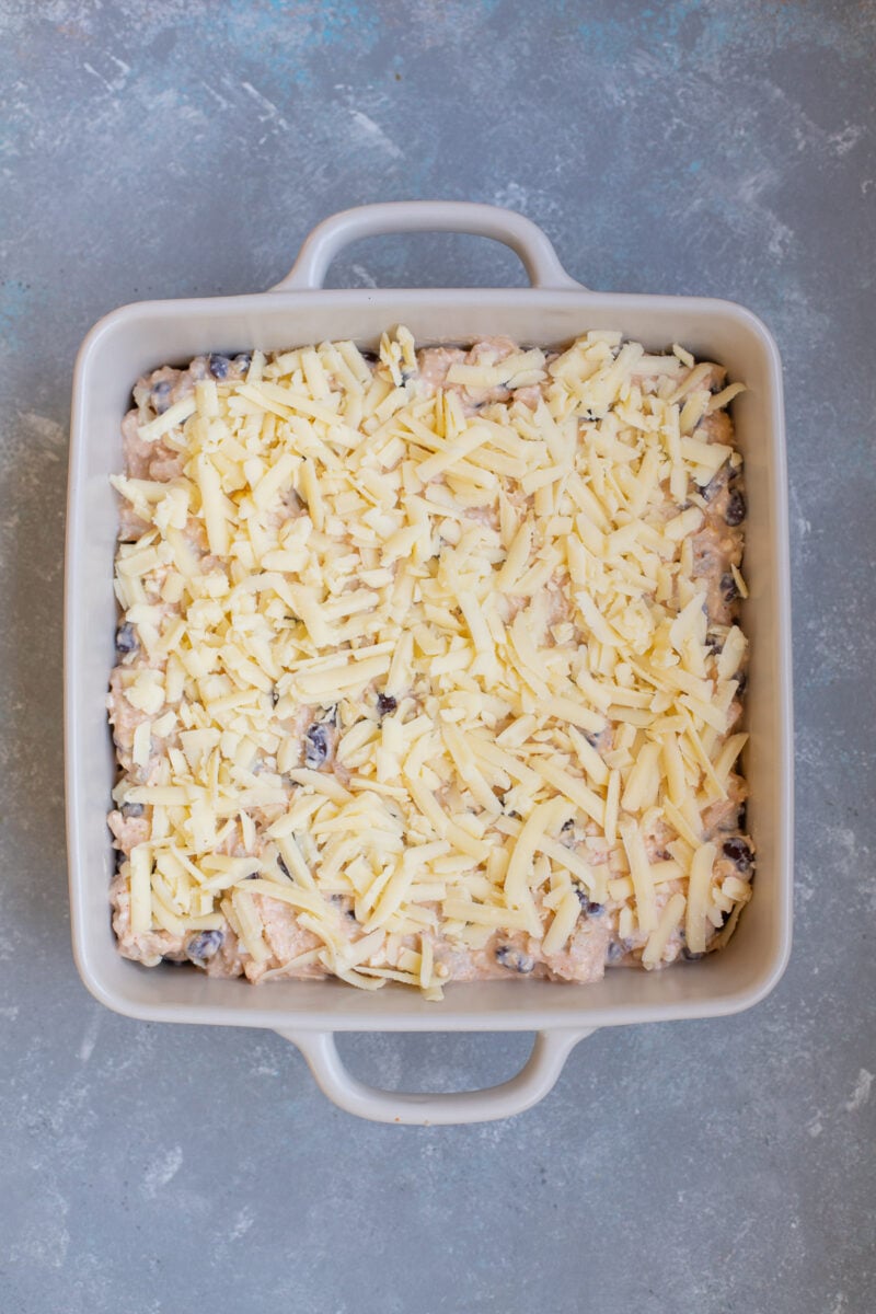 Uncooked chicken enchilada dip in a baking dish.