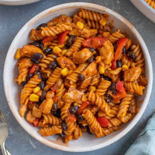 An overhead shot of chicken enchilada pasta in a bowl with another bowl on the side.