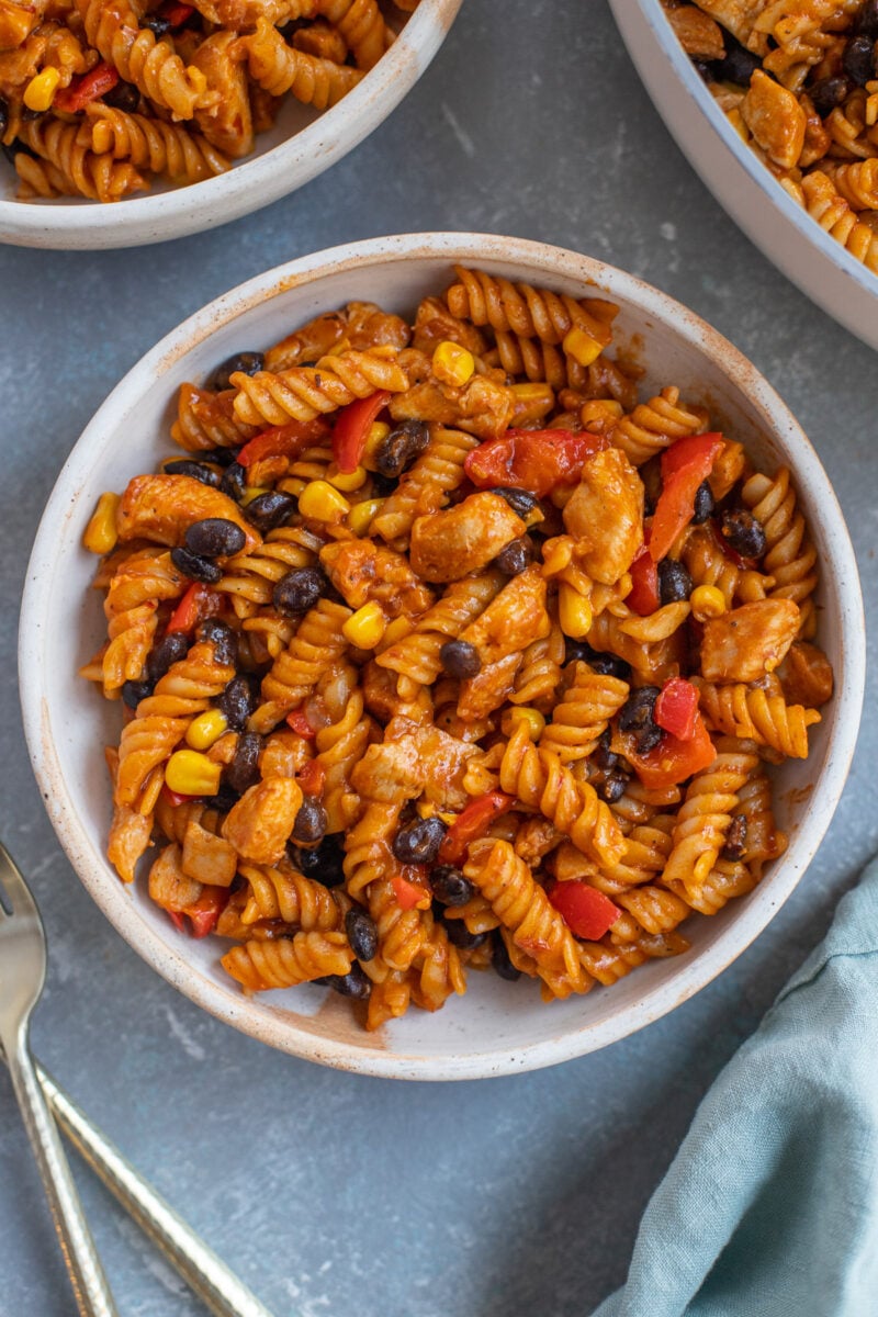 An overhead shot of chicken enchilada pasta in a bowl with another bowl on the side.