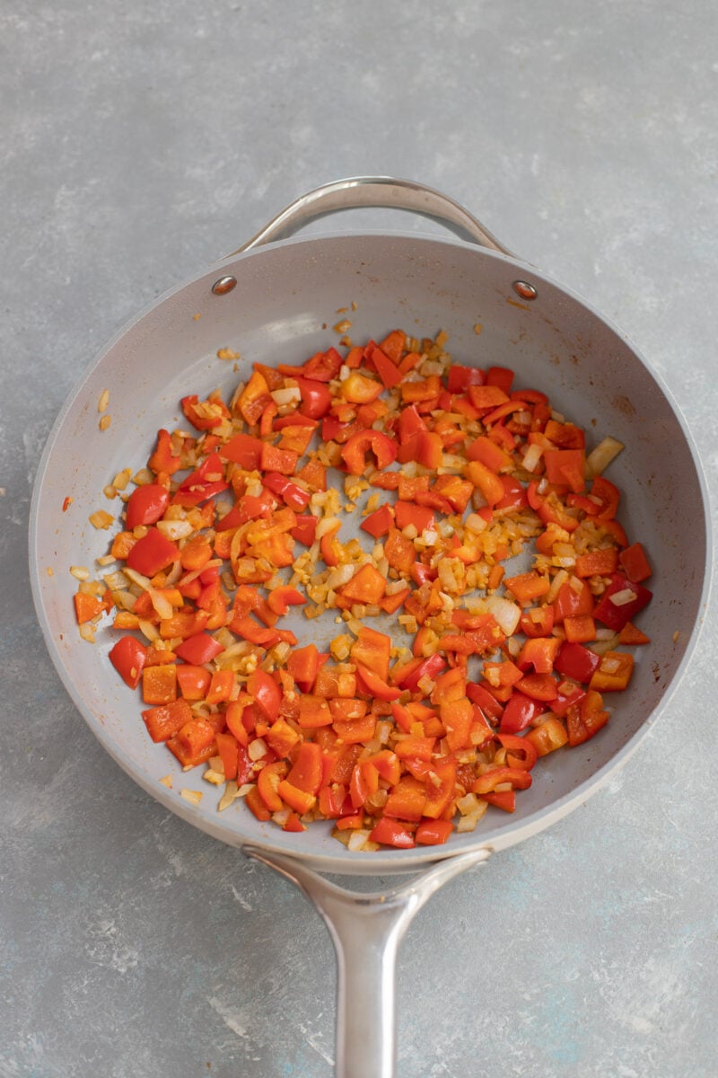 Onions and bell peppers sautéed in a skillet.