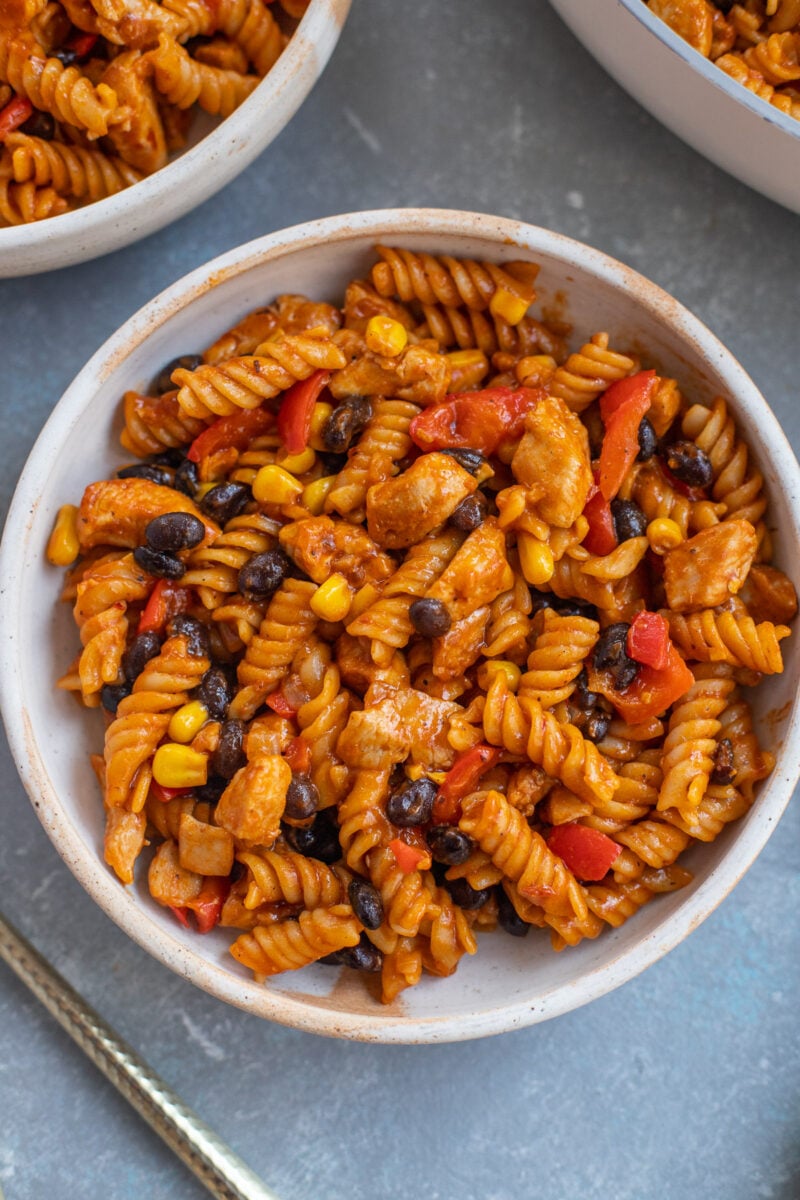 An overhead shot of chicken enchilada pasta in a bowl with another bowl on the side.