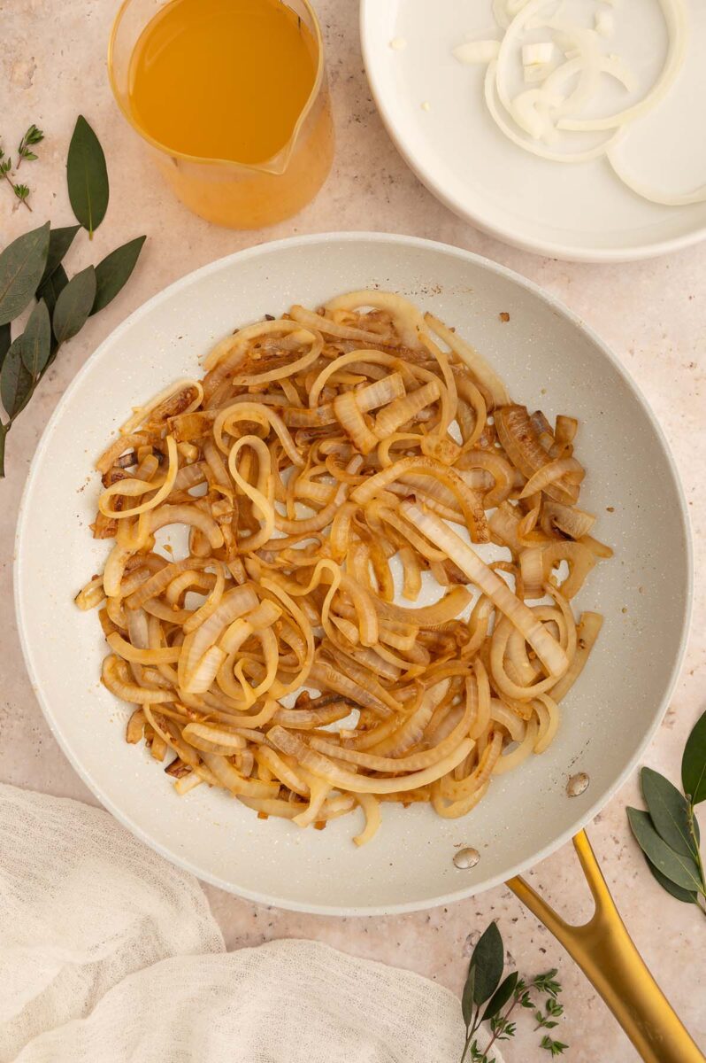 Onions and garlic cooking in a skillet to make french onion orzo.