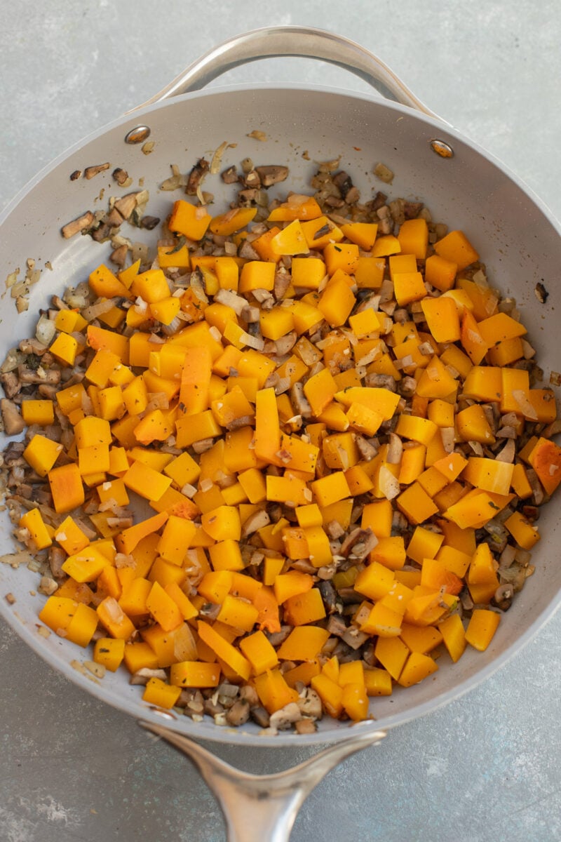 Onion, garlic, mushrooms, spices and butternut squash in a skillet after cooking. 
