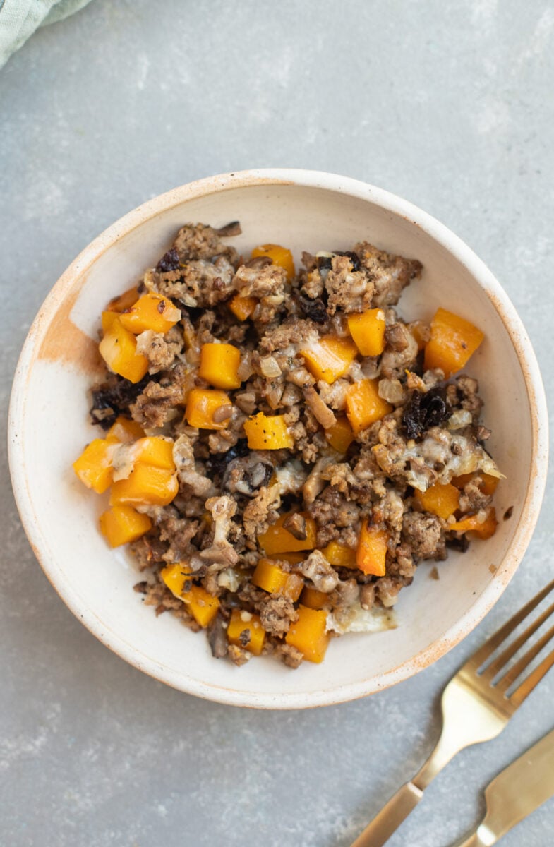 A serving of Ground Beef Butternut Squash on a white plate with a fork on the side.