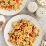 Red Pepper Chicken Orzo on a white plate with another plate on the side.