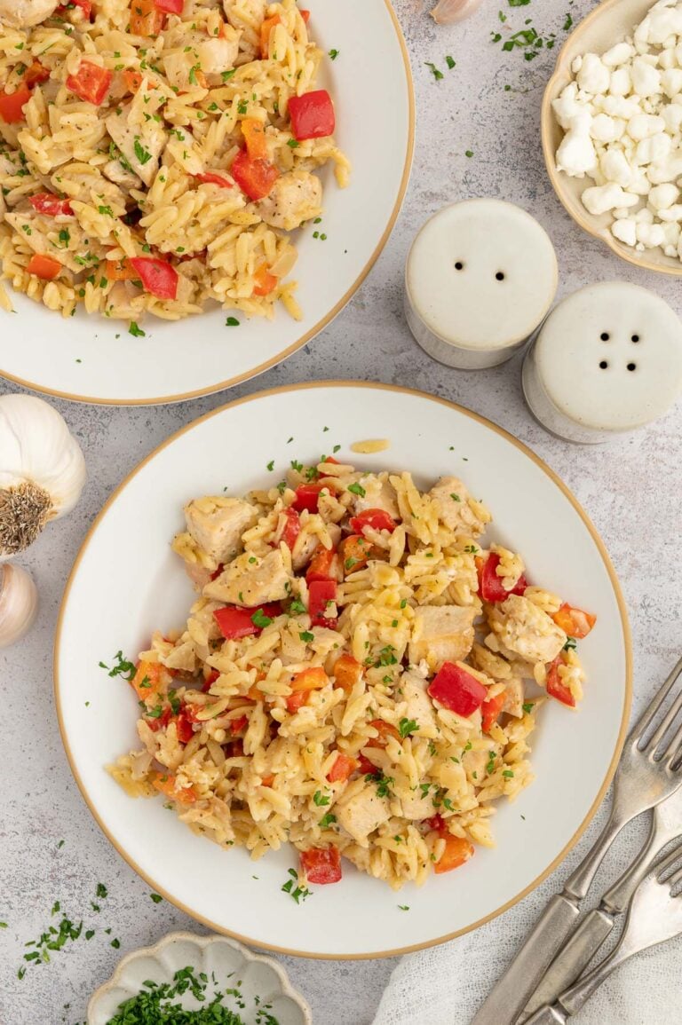Red Pepper Chicken Orzo on a white plate with another plate on the side.
