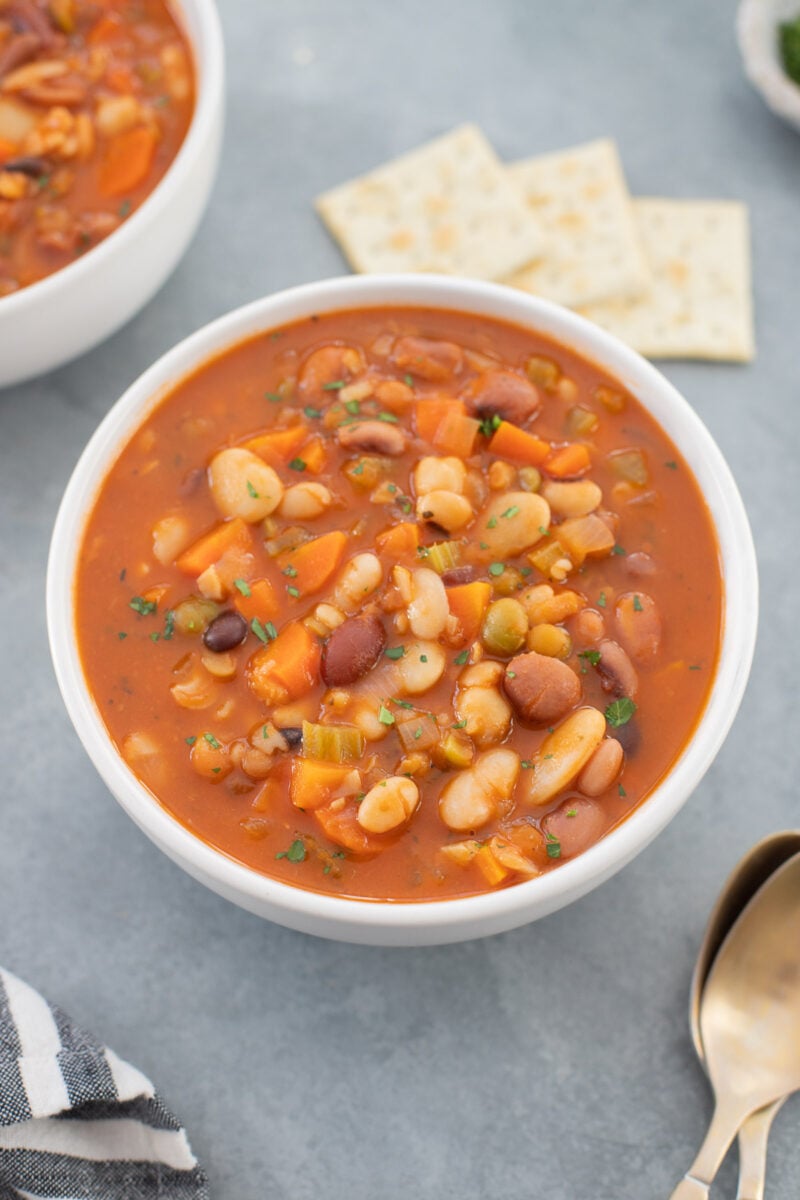 a white bowl full of easy bean soup on a grey background