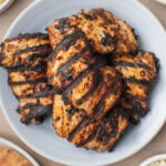 Grilled Greek Yogurt Marinated Chicken Thighs stacked on a plate.