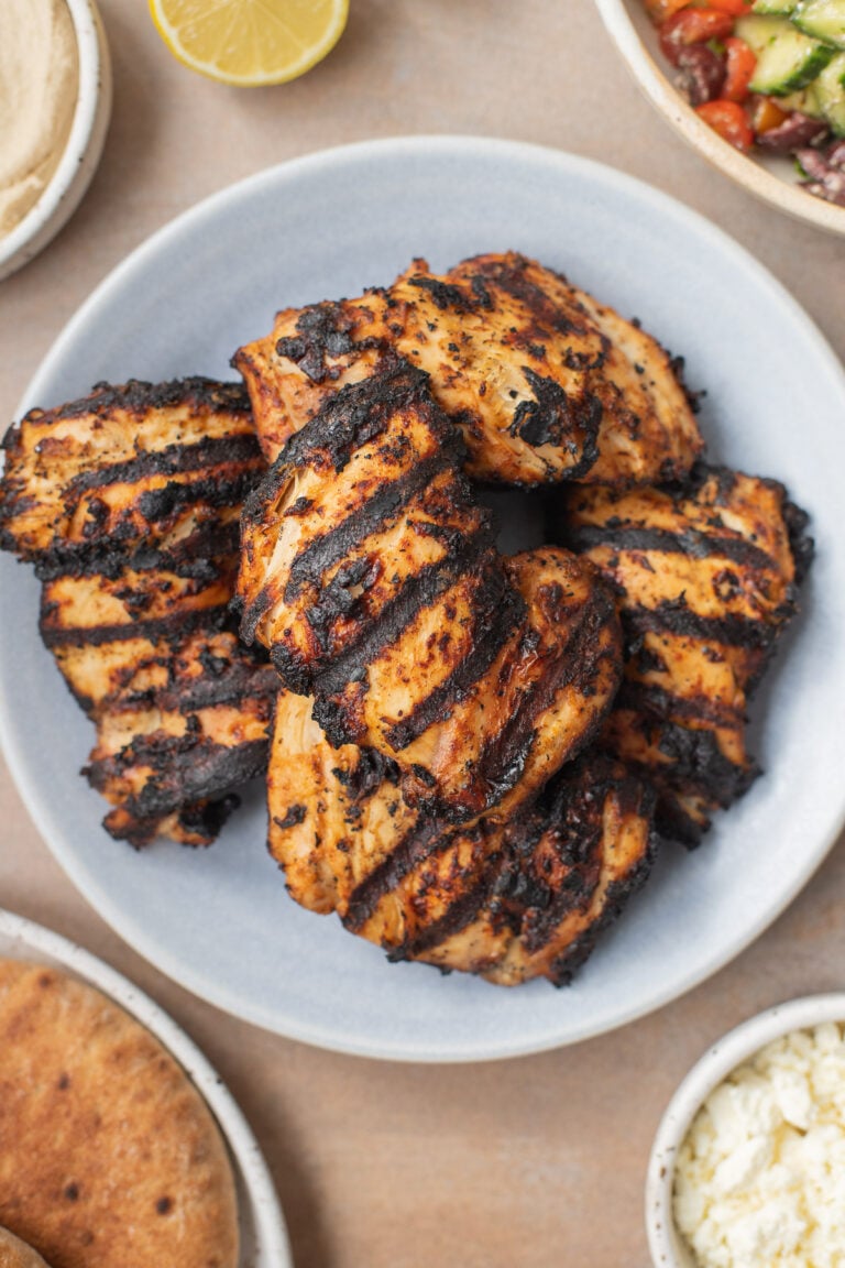 Grilled Greek Yogurt Marinated Chicken Thighs stacked on a plate.