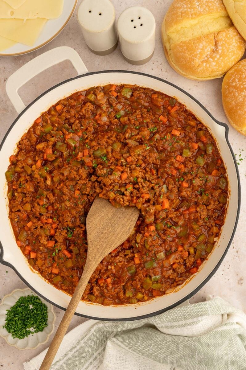 Healthy Sloppy Joes mixture in a skillet with a wooden spoon in the mixture.