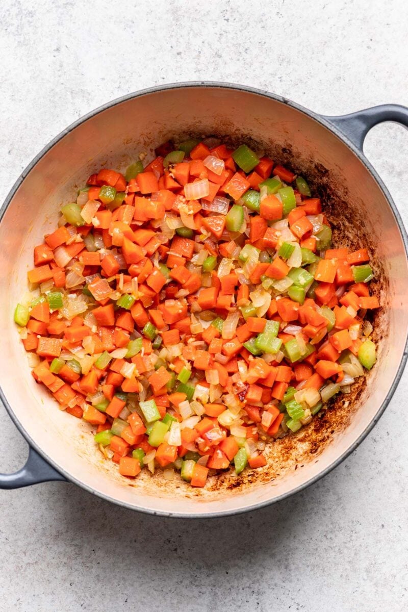Sauteed vegetables for greek lemon chicken soup in a dutch oven pot.