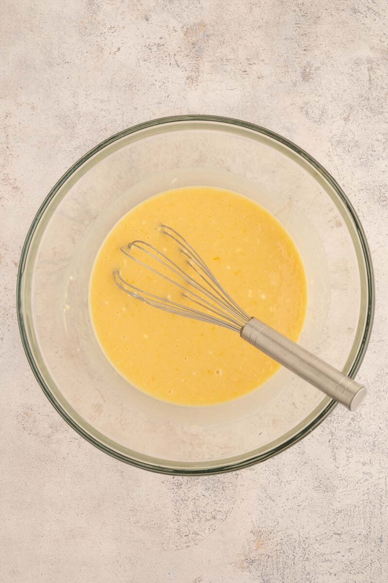 Wet ingredients for apple protein muffins in a glass bowl with a whisk in it.