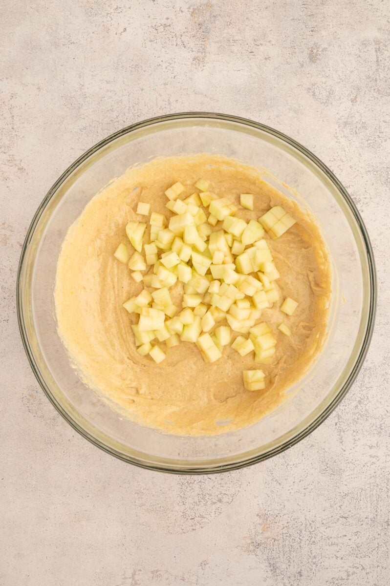 Diced apples in a bowl of apple protein muffin batter before folding in. 