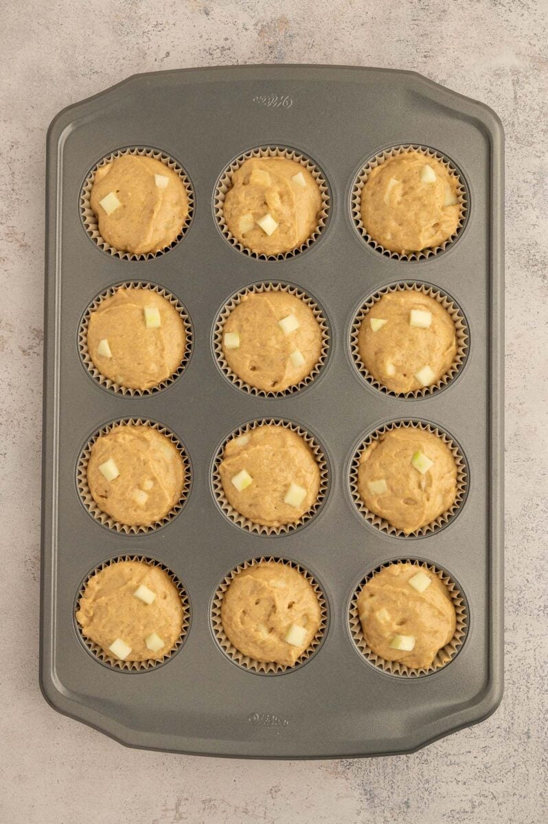 Unbaked apple protein muffins in a 12 count muffin pan.