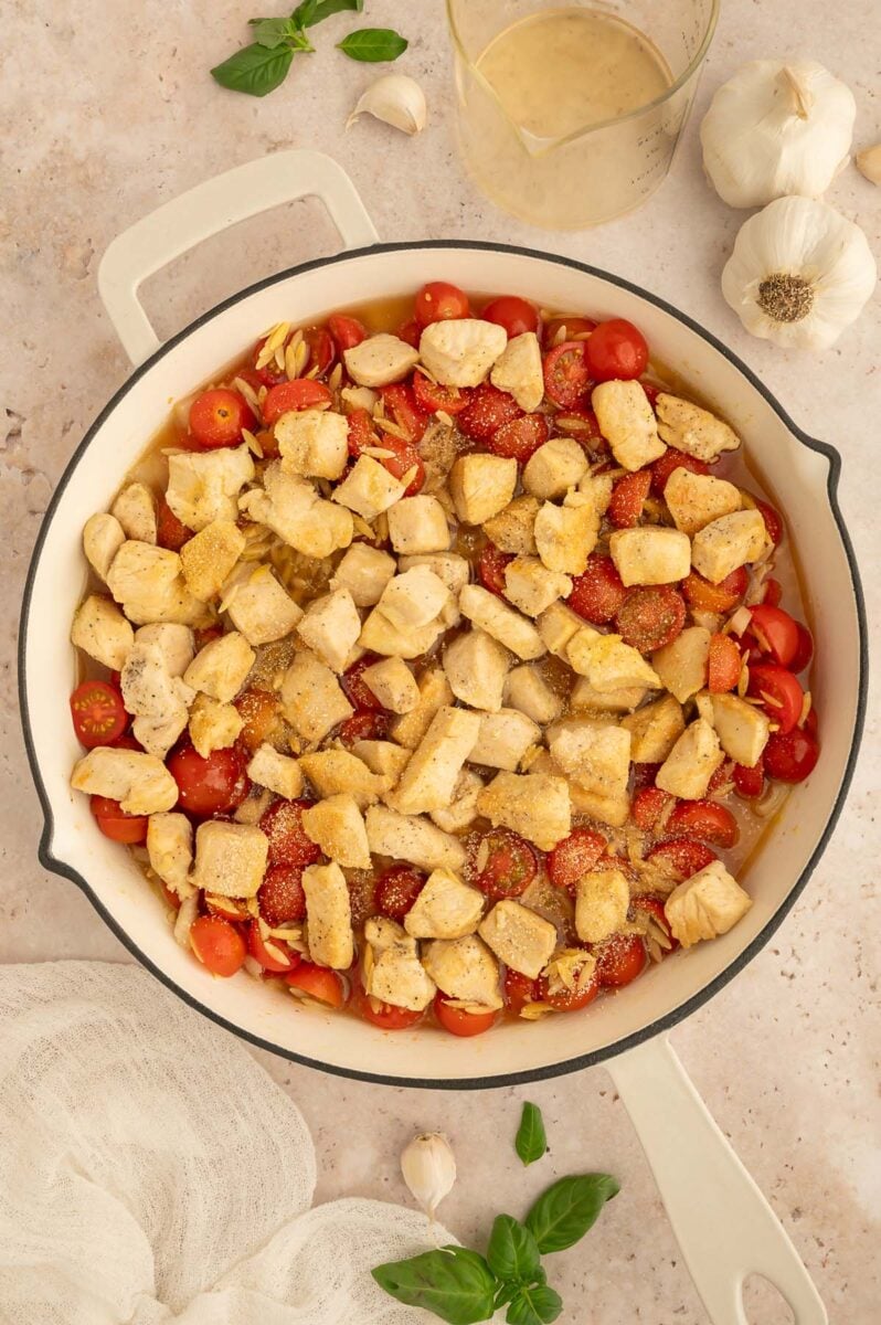 Ingredients for chicken caprese orzo in a skillet before fully cooking. 