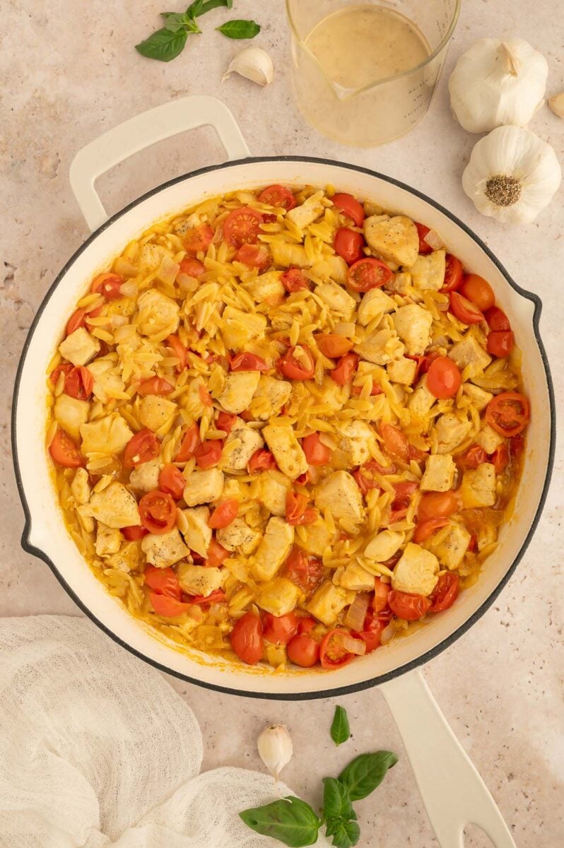 Chicken caprese orzo in a skillet before adding the mozzarella and basil.