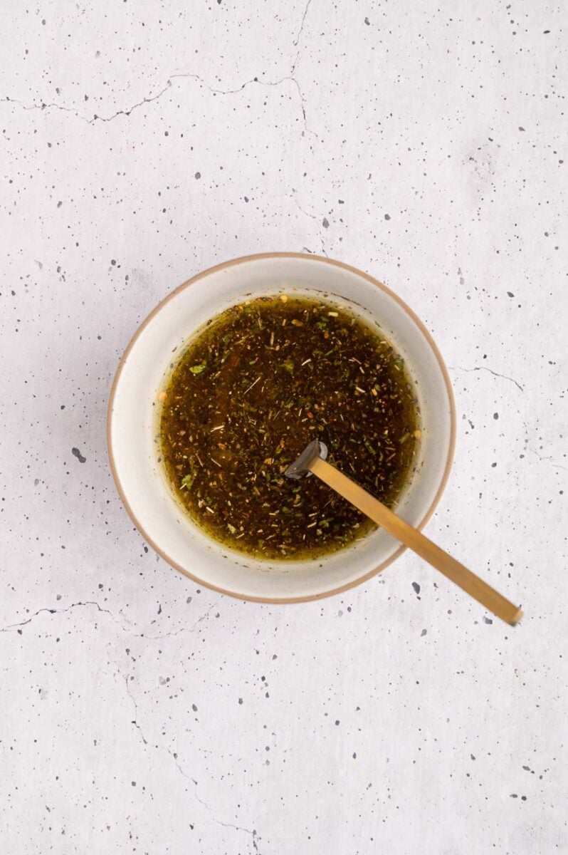 Italian dressing in a small bowl with a spoon in it. 