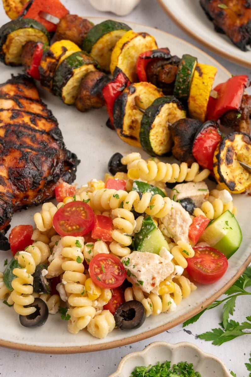 High protein pasta salad on a plate with bbq grilled veggies and balsamic grilled chicken.