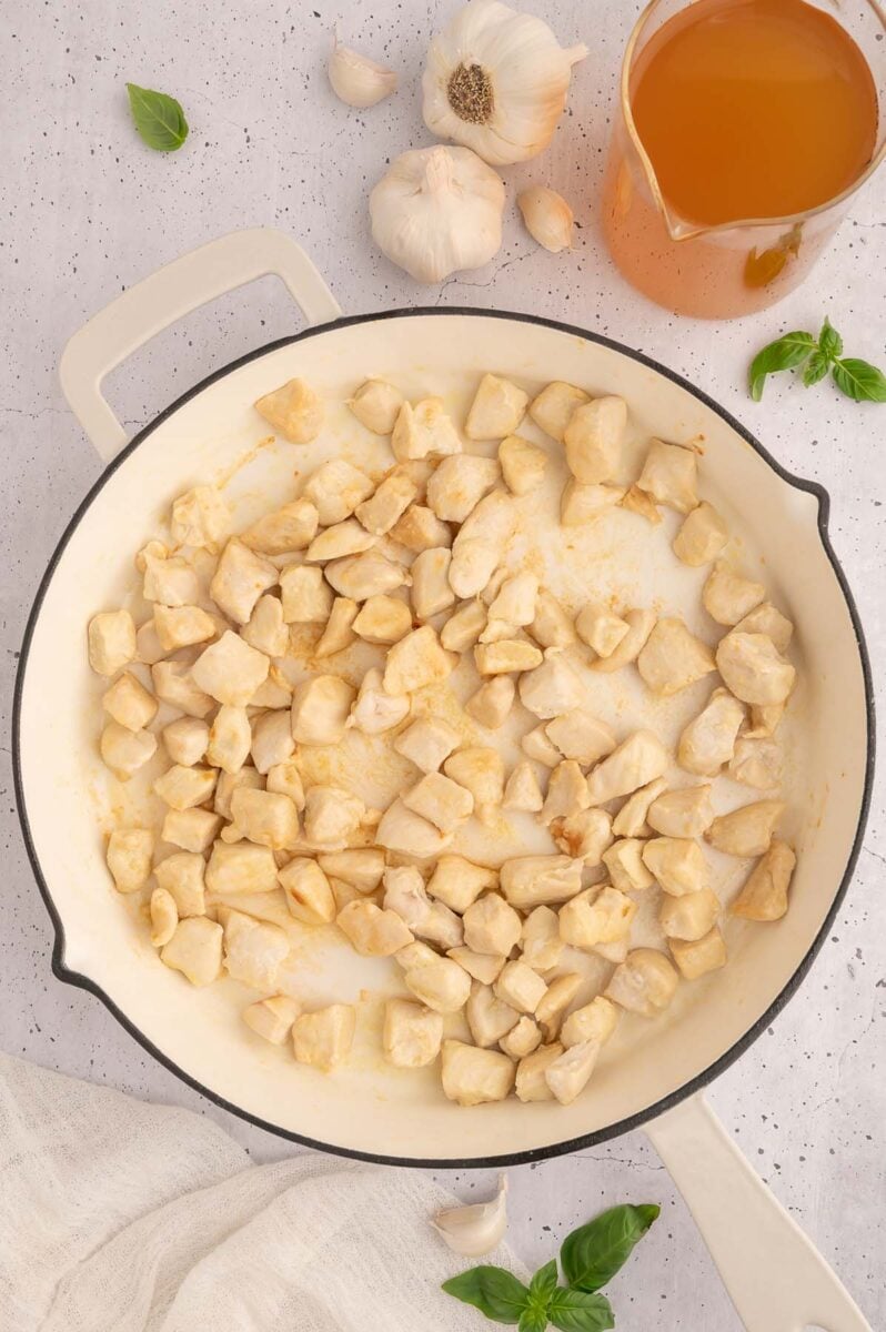 Chicken pieces in a skillet cooking.