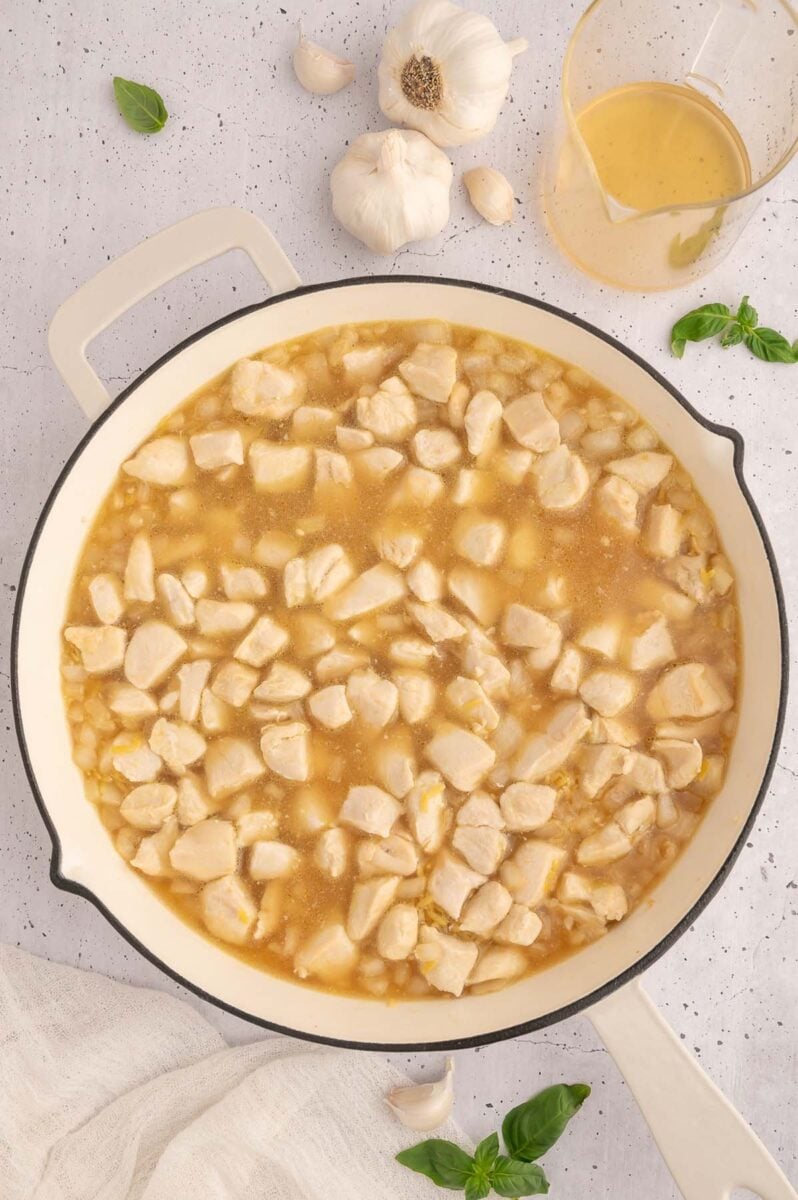 Cooked chicken added to a skillet with orzo. 