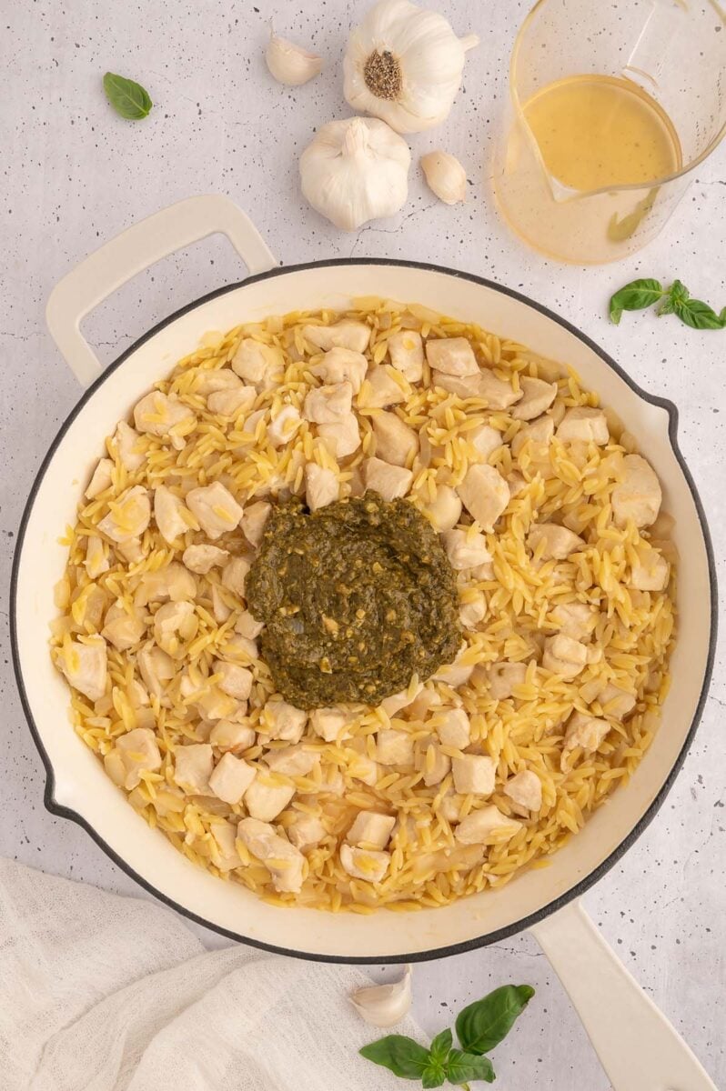 A skillet with pesto chicken orzo before the pesto is stirred in. 