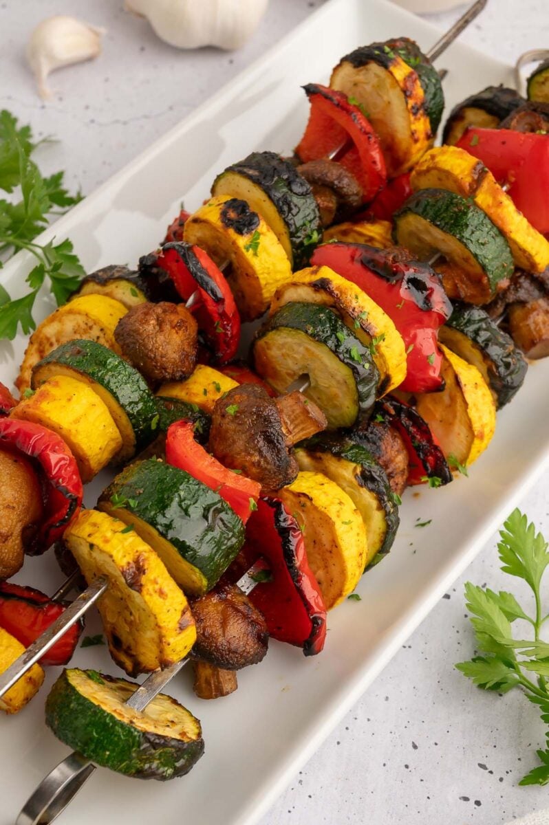 Grilled veggie kebabs on a white plate. 