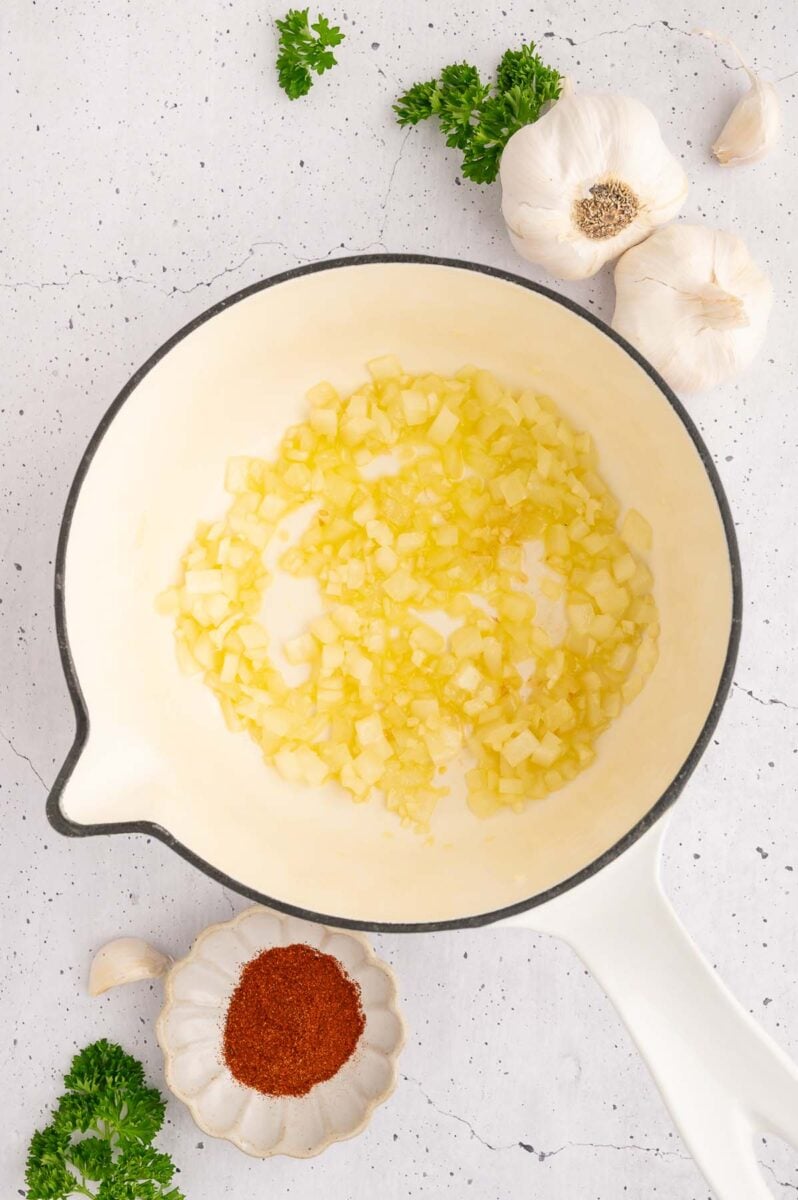 Onions and garlic sauteing in olive oil in a pot.