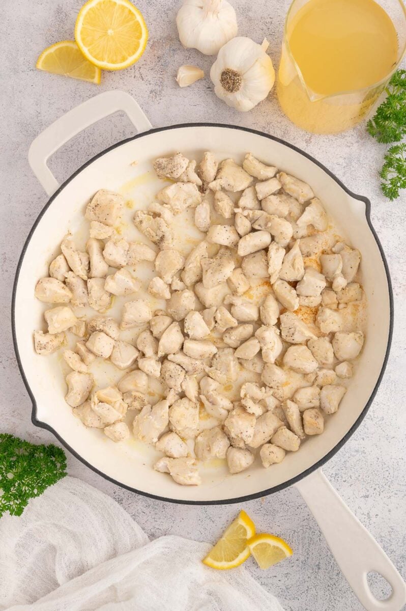 Chicken pieces cooking in a skillet.