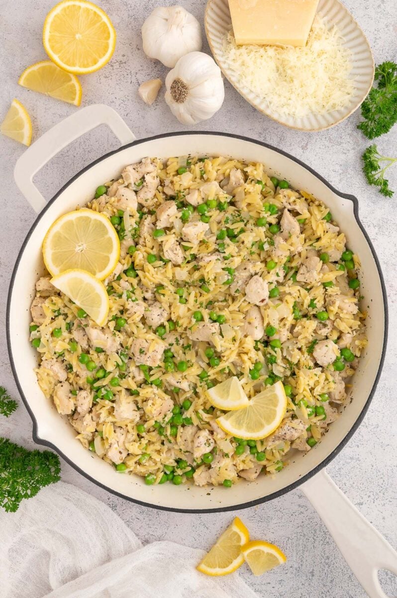 Lemon Chicken Orzo in a skillet garnished with lemon slices.