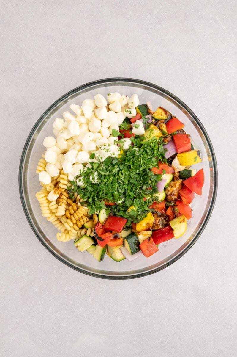 Ingredients for grilled vegetable pasta salad in a large bowl before mixing together. 